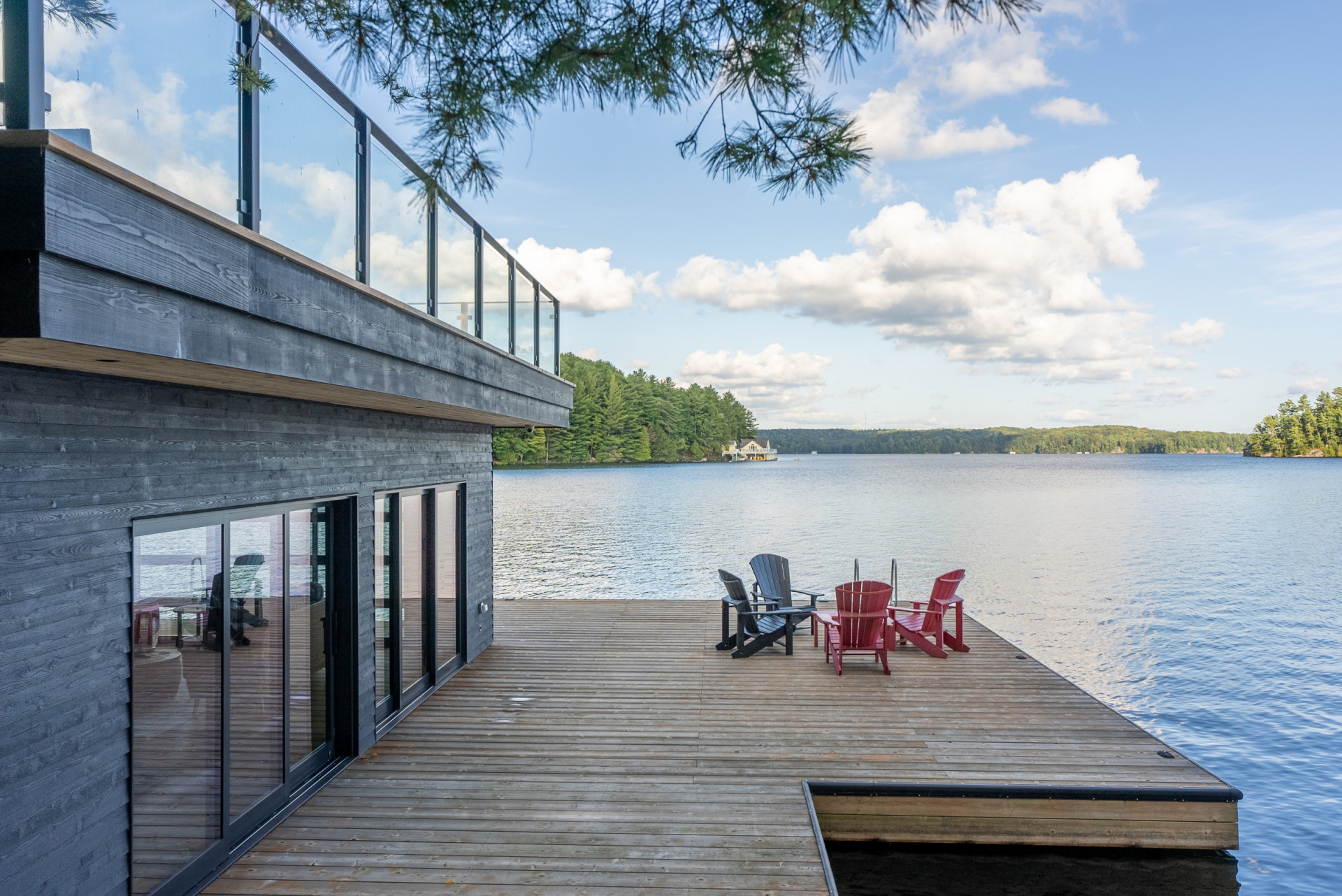 Boathouse dock with red Muskoka chairs looking out over an open lake — built work by Corbin Patten Designs